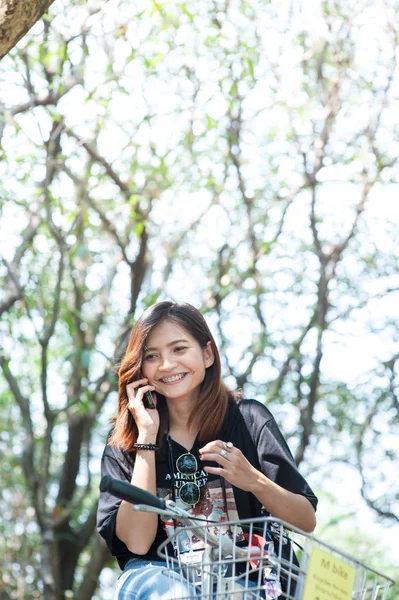 Hermosa chica en una bicicleta hablando en el teléfono móvil en el parque —  Fotos de Stock