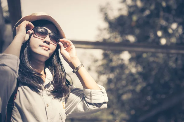 Όμορφη νεαρή ασιατική γυναίκα φοράει στρογγυλή καπέλο σε ένα πάρκο, ταξιδεύουν σε μια καλοκαιρινή μέρα — Φωτογραφία Αρχείου