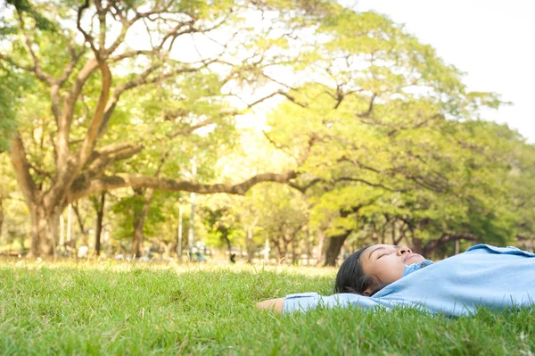 Mulher bonita e jovem relaxante no parque, no prado de grama verde — Fotografia de Stock