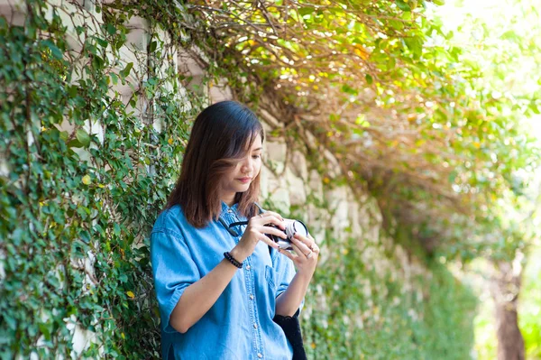 Bokovky žena fotografování s fotoaparátem retro film v květinové zahradě městského parku, krásná dívka, fotografoval v starý fotoaparát — Stock fotografie