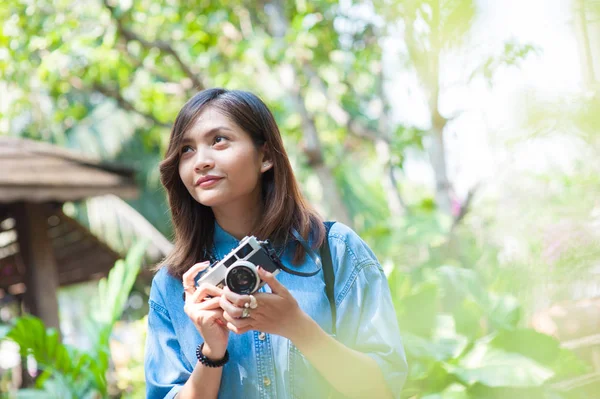 Hipster mulher tirar fotos com câmera de filme retro no jardim de flores do parque da cidade, linda menina fotografada na câmera velha — Fotografia de Stock