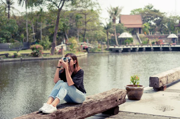 Хіпстерська жінка робить фотографії з ретро плівковою камерою у відкритому міському парку, красива дівчина сфотографована в старій камері — стокове фото