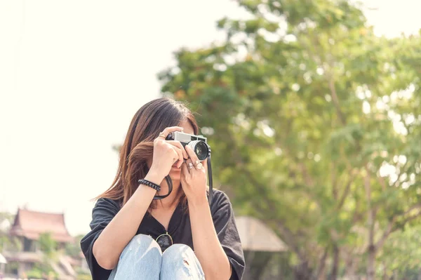 Hipster kvinna att ta foton med retro filmkamera i utomhus stadspark, vacker flicka fotograferade i den gamla kameran — Stockfoto