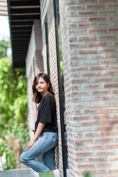 El verano, la moda y el concepto de la gente - mujer joven posando al aire libre sobre la pared de ladrillo, moda callejera —  Fotos de Stock