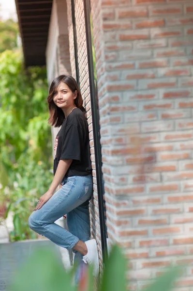 El verano, la moda y el concepto de la gente - mujer joven posando al aire libre sobre la pared de ladrillo, moda callejera —  Fotos de Stock