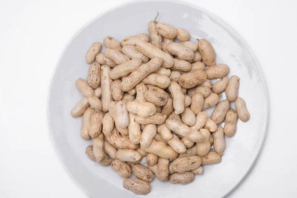 Amendoins secos na placa branca no fundo branco — Fotografia de Stock