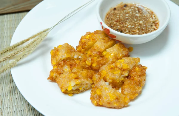 Sweet Corn Fritters,Crispy fried corn in a white plate on bamboo mat -table,Snacks Thai style.