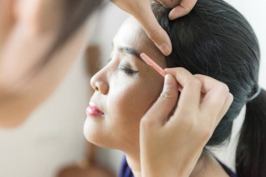 Yüz kadının, kaşlarını cımbızla depilating koparma kadın kalıcı makyaj yapma güzellik uzmanı.