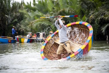 HOI AN, VİETNAM-9 Aralık 2019: Balıkçı yuvarlak sepet teknede döndüğünü gösteriyor. Cam Thanh köyünde eşsiz bir Vietnamlı..