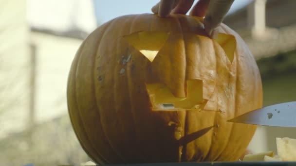 Vader kerft met mes griezelig Halloween-hoofd. Iemands handen snijden mes de pompoen spooky mond met tanden. — Stockvideo