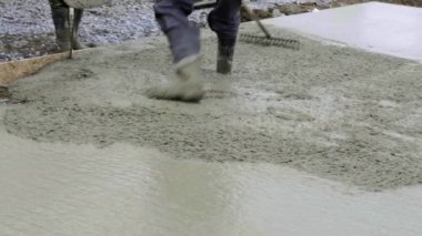 İşçiler inşaat alanında çalışıyor, zemin çalışıyor. Aile evinin temellerine beton dökme pompasının ayrıntıları. Beton karıştırma pompası temel plaka üzerinde çalışır, arkaplanda gökyüzü