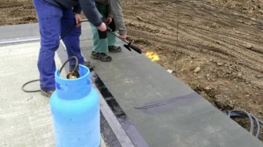 Su yalıtım yapıştırma için yazıcı. Yalıtım çalışan Müstakil Ev, propan gaz brülörlü Bodrum katında su yalıtımı yapım. Rulo su yalıtımı montajı
