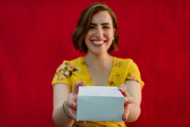 Elinde hediyeyle gülümseyen kadın.