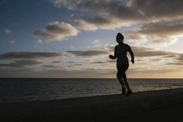 girl running to left, against light with sky and storm clouds