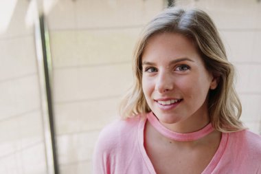 güzel sarışın beyaz kadın kameraya bakıyor ve gülümsüyor yeşil gözlü ve pembe gömlekli, yakın plan