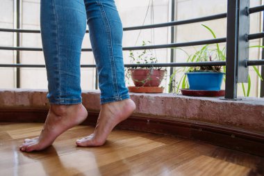 Mavi kotlu beyaz bir kızın yalın ayak, parmak uçlarında, ahşap zeminde, güzel bitkilerle