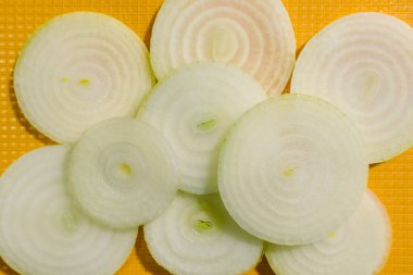 Sarı kesme tahtasındaki beyaz soğan dilimlerinden yapılmış bir kalıp. Üst görünüm.