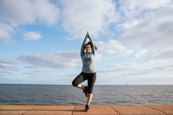 Deniz kenarında yoga yapan genç bir kadın. Spor ve sağlıklı yaşam tarzı.