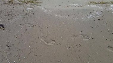 Kumlu bir plaj üzerinde kadın insan ayak izleri