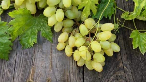 Wis van witte druiven met bladeren op houten tafel — Stockvideo