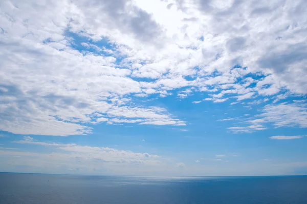 Blue sky with clouds over the sea stretching into the distance