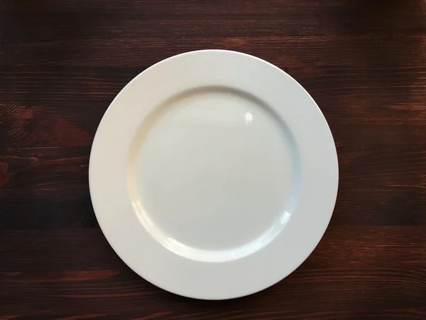 Empty white plate on wooden table — Stock Photo, Image