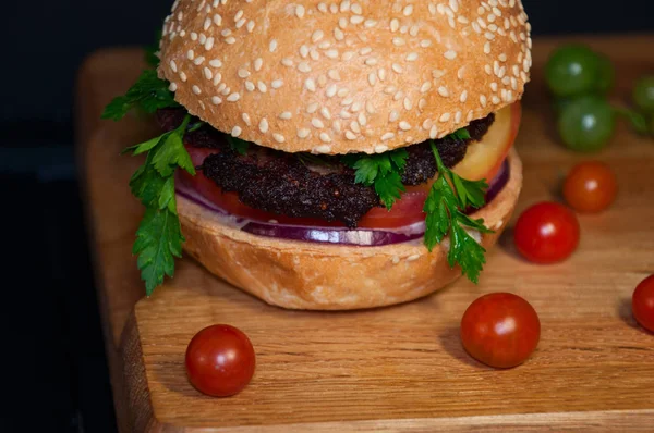 Hambúrguer saboroso com costeletas de carne servido em uma tábua de madeira — Fotografia de Stock