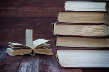 eski kitaplar açık kitap yakınındaki kahverengi ahşap yüzeyde yığını