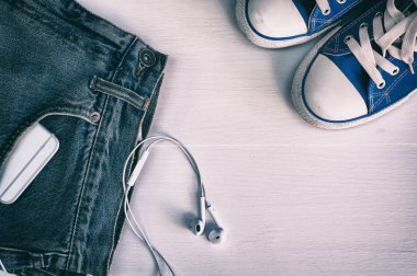 Soluk mavi kot pantolon ve Beyaz ahşap zemin üzerinde mavi spor ayakkabı