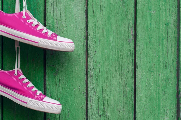 亮粉色双体育运动鞋挂在木墙 cra — 图库照片
