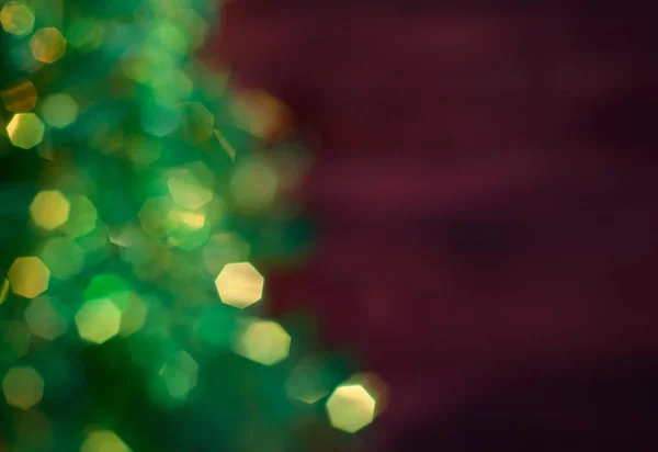 Blurred Christmas tree with garland, green bokeh on a dark red b — Stock Photo, Image