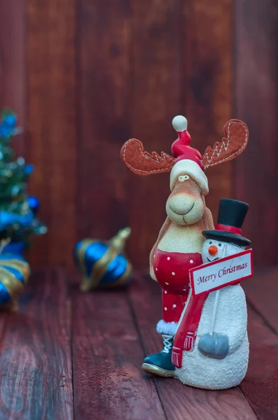 Fondo de Navidad con renos y un muñeco de nieve sobre una madera marrón — Foto de Stock