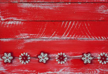 Eski püskü ahşap yüzeyde kırmızı keçe kar taneleri ile çelenk