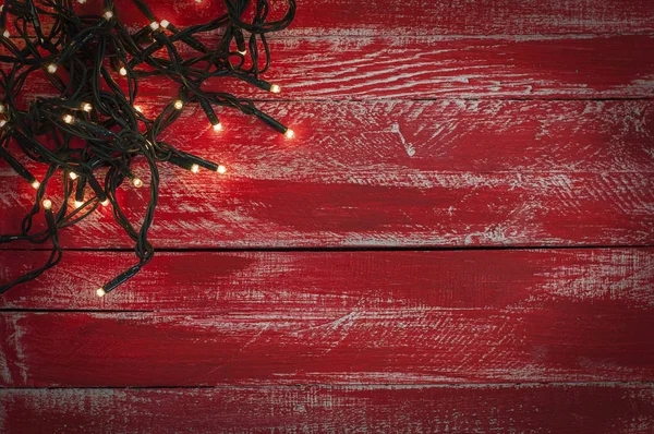 Christmas garland with small light bulbs on the red shabby woode