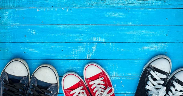 Drie paar sneakers dragen op een blauwe houten oppervlak, bovenaan vi — Stockfoto