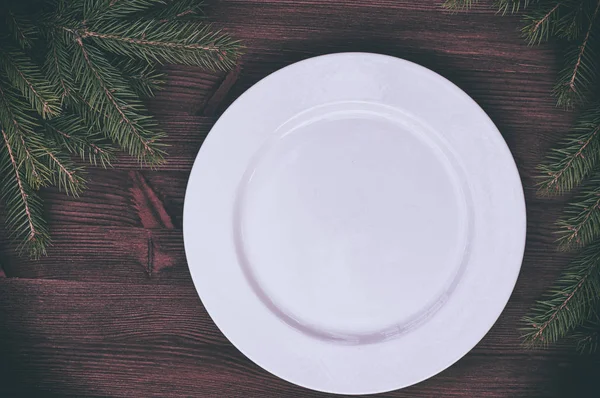 Белая пустая тарелка с зеленой веткой дерева на деревянном серфе — стоковое фото