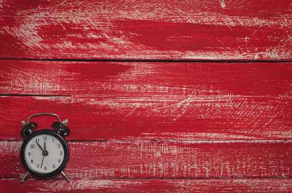 Velho relógio preto no fundo vermelho de madeira — Fotografia de Stock