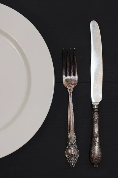 Setengah piring putih kosong, pisau antik dan garpu di atas meja — Stok Foto