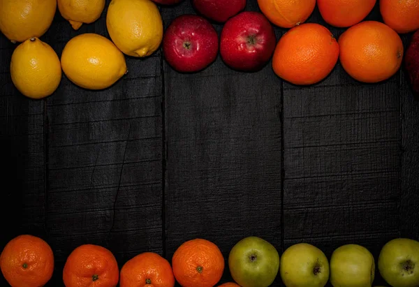 Ripe fruits are laid out on the perimeter on a black wooden back — Stock Photo, Image