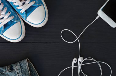 Spor ayakkabı siyah ahşap surfac Tarih ve kulaklık ile Smartphone