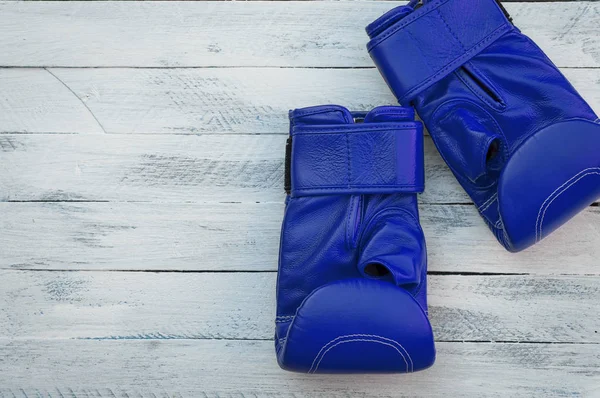 Par de guantes de boxeo azules sobre una superficie de madera blanca —  Fotos de Stock
