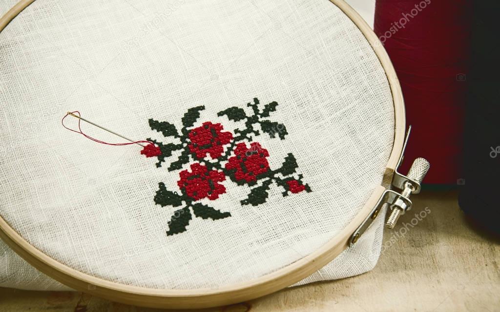 Hand embroidery cross-stitch flower ornament on a white fabric