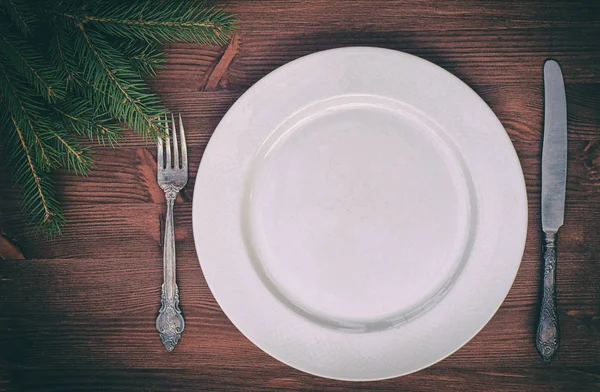 Белая тарелка с ножом и вилкой на коричневой деревянной поверхности — стоковое фото
