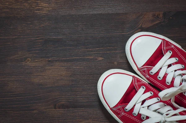 Par röda sneakers på en brun trä yta — Stockfoto