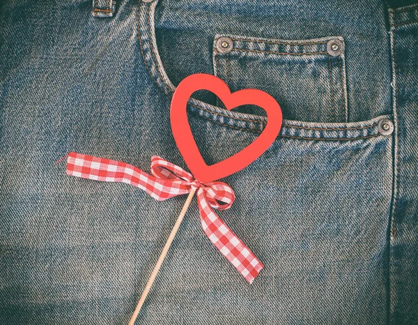 Červené dřevěné srdce na pozadí modré sepraných džínů — Stock fotografie