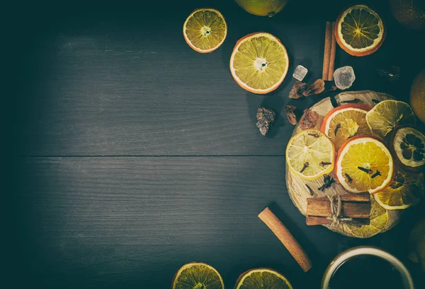 Thee in een mok met gedroogde citrus fruit en specerijen op een zwarte woode — Stockfoto