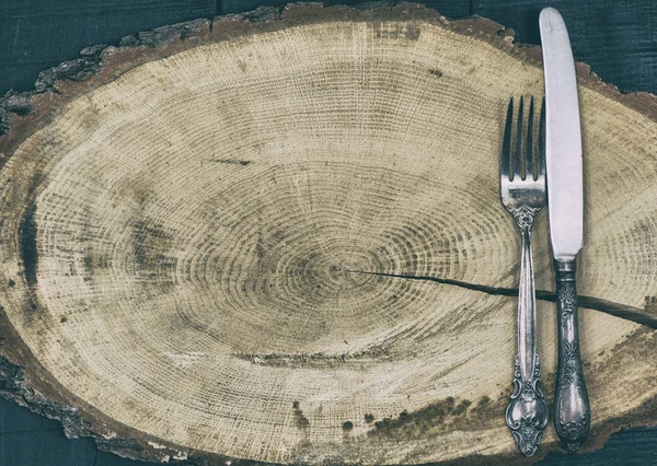 Tenedor y cuchillo en un tocón de madera marrón, espacio vacío — Foto de Stock