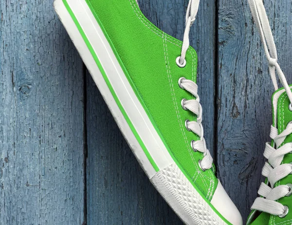 Ярко-зеленые текстильные кроссовки висят на белом кружеве — стоковое фото