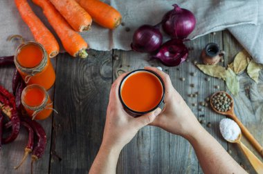 Bir demir kupa ile havuç suyu tutan iki eller 