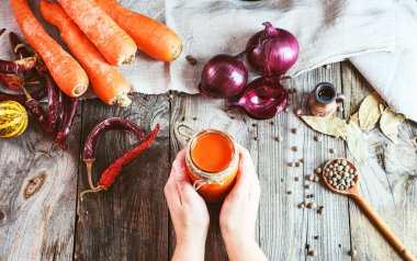 bir kavanoz bir bardak taze havuç juic tutan iki eller